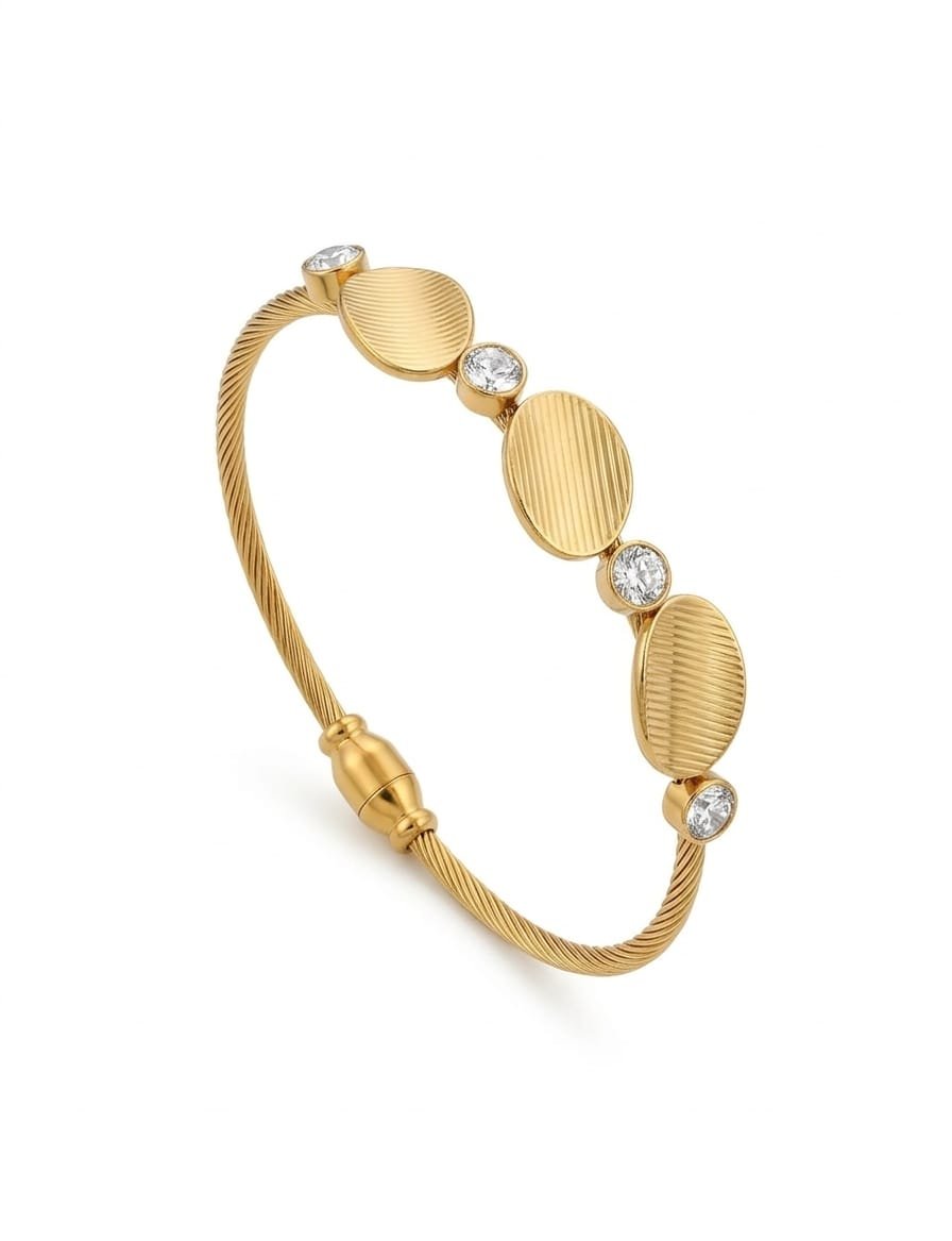 Close-up of a gold twisted cable bangle with three textured oval discs and four sparkling crystals