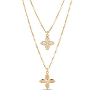 Close-up of a double-layered gold necklace with a crystal pavé clover and a solid gold flower pendant