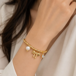 Gold Plated Bamboo Motif Charm Bangle from justjewel.co.in featuring pearl and bow charms.
