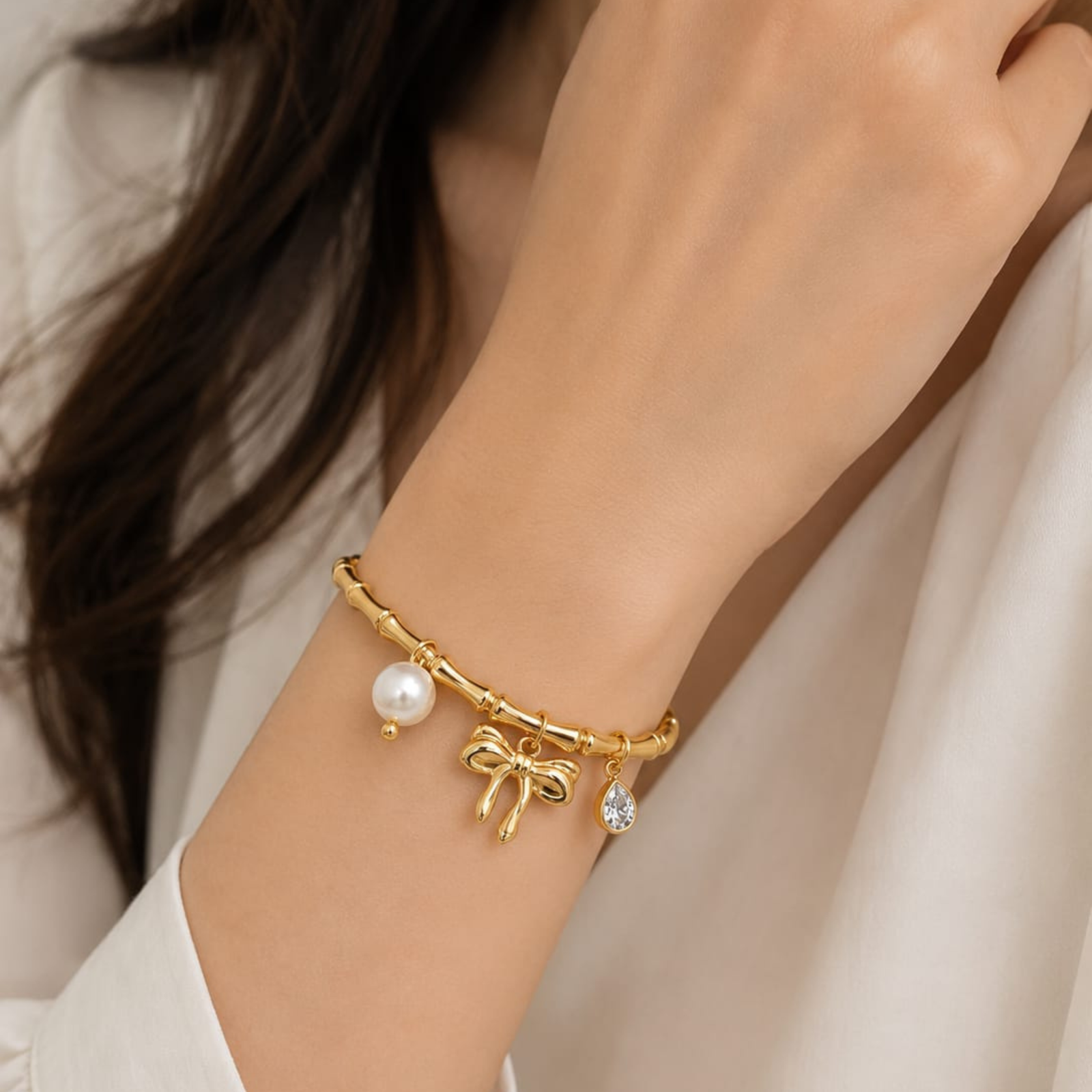 Gold Plated Bamboo Motif Charm Bangle from justjewel.co.in featuring pearl and bow charms.